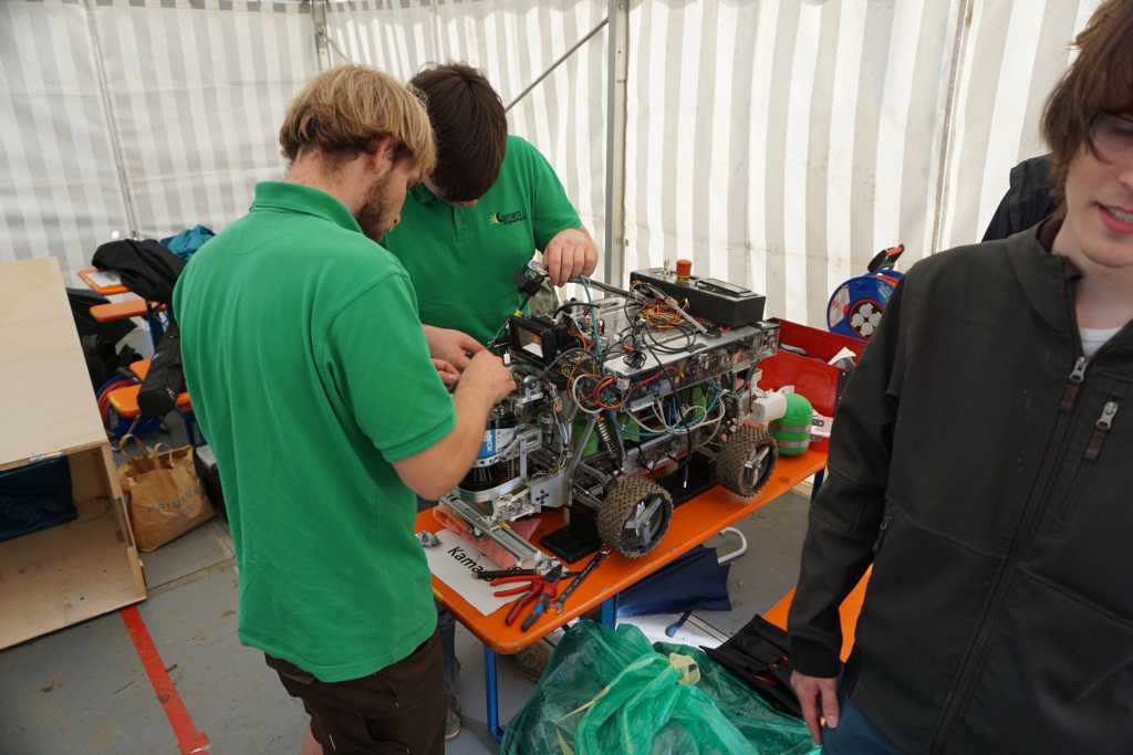 Beteigeuze aufgebockt auf einem Biertisch mit zwei Kamaros mit grünem Poloshirt arbeiten am Roboter